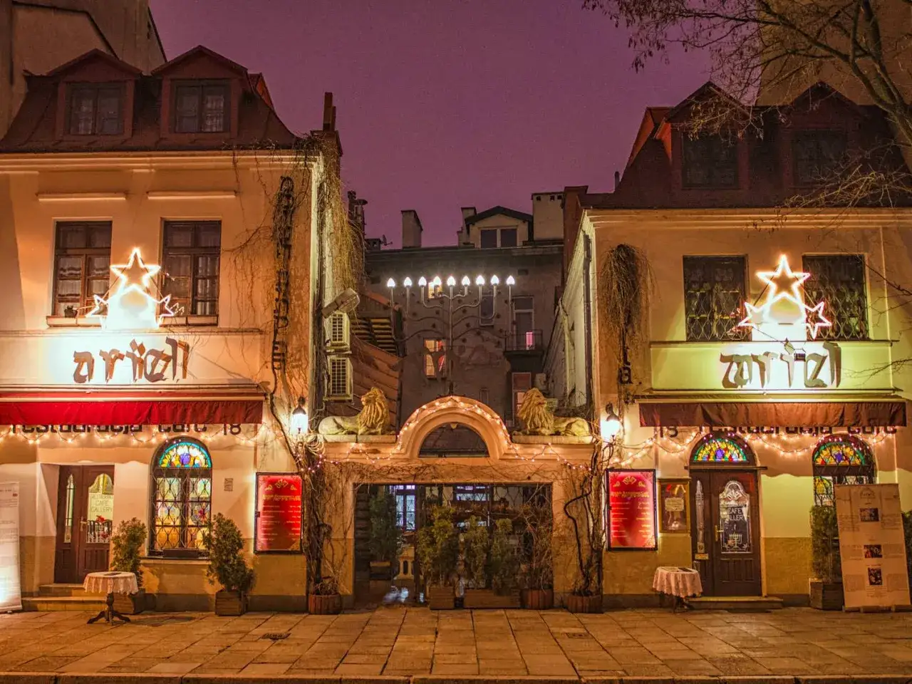 Wieczorem rozświetlony **quartiere ebraico Cracovia** z neonami i gwiazdami.