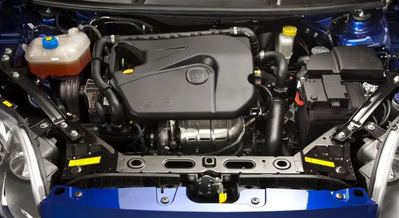 Silnik fiat bravo 1.4 t-jet w komorze pod niebieską maską. Widać turbosprężarkę i osprzęt.