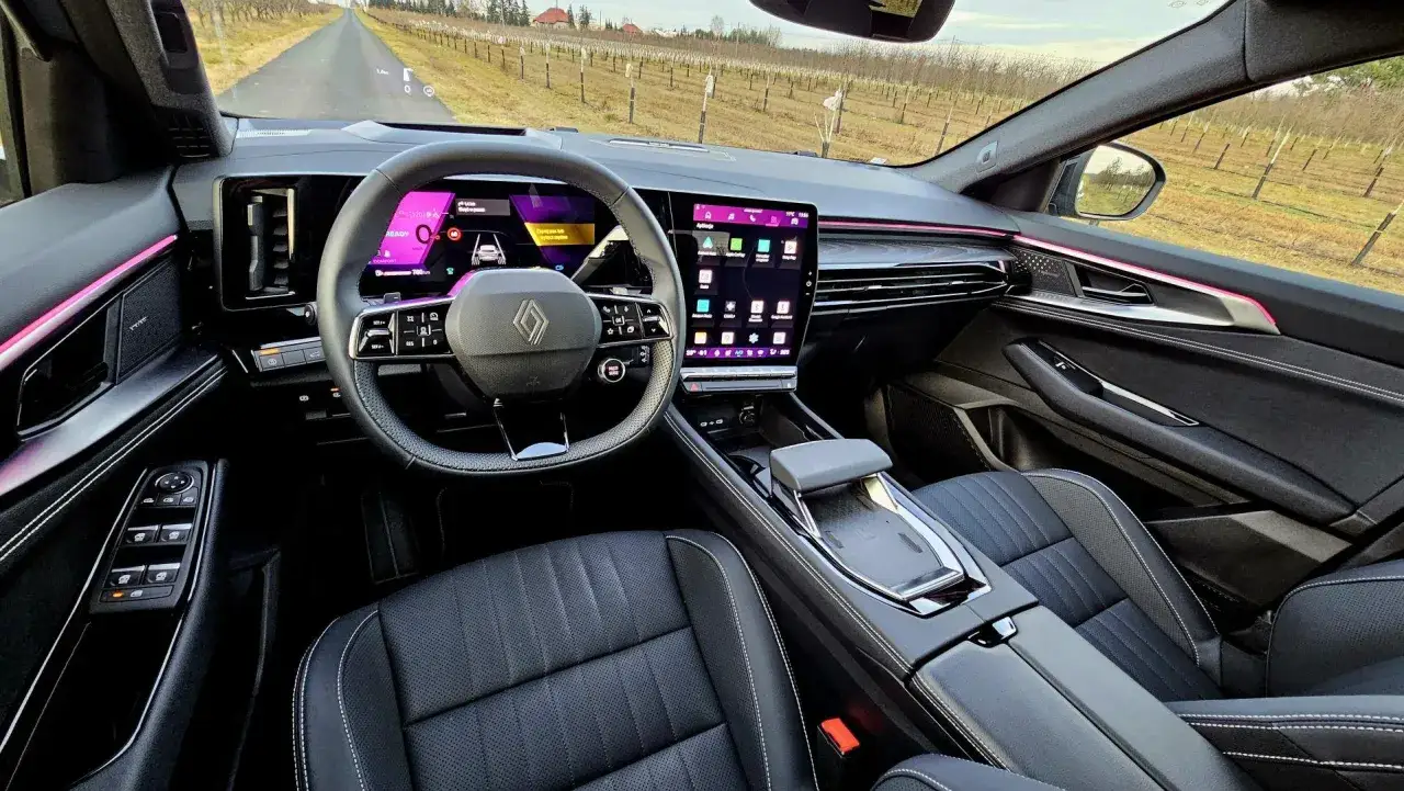 Wnętrze Renault Espace 2024 z nowoczesnym ekranem multimedialnym i cyfrowymi zegarami. Widok z perspektywy kierowcy na drogę wśród winnic.