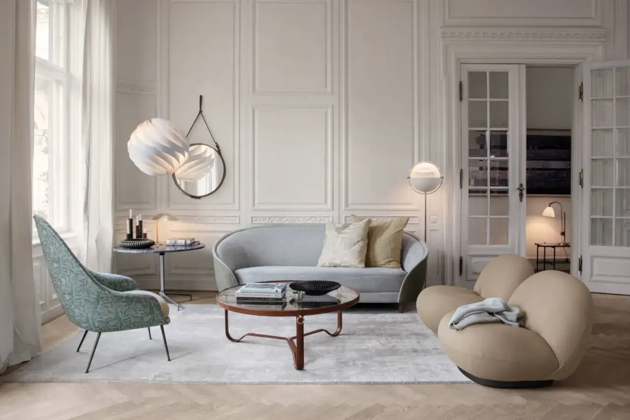 A living room showcasing a modern furniture style guide: a patterned armchair, grey sofa, and unique tan chair.