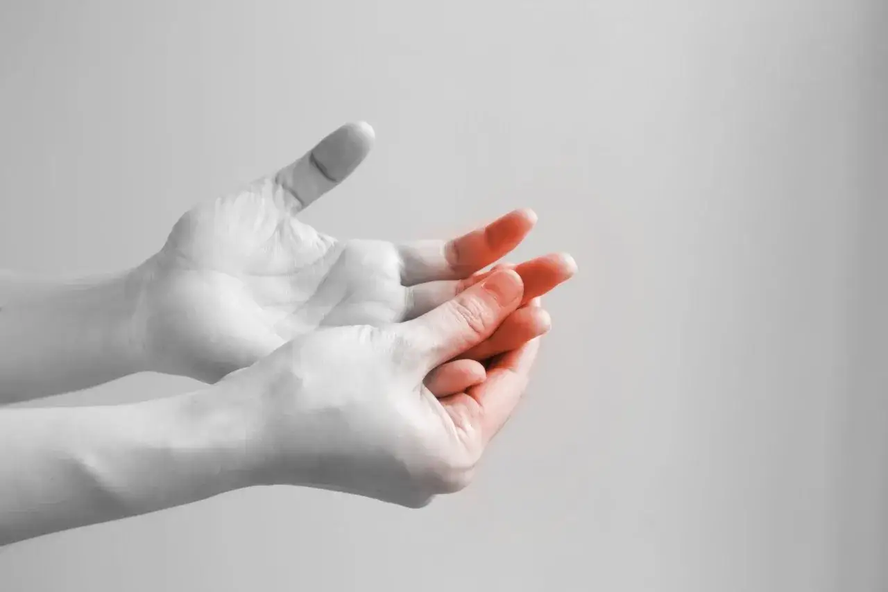 Dłonie z zaczerwienionymi palcami, symbolizujące neuropatię alkoholową, która może utrudniać spokojny sen.