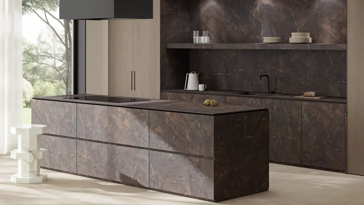 L'isola e le ante della cucina presentano un'elegante finitura in marmo scuro, un esempio di **colori cucine moderne** che unisce lusso e praticit&agrave;.