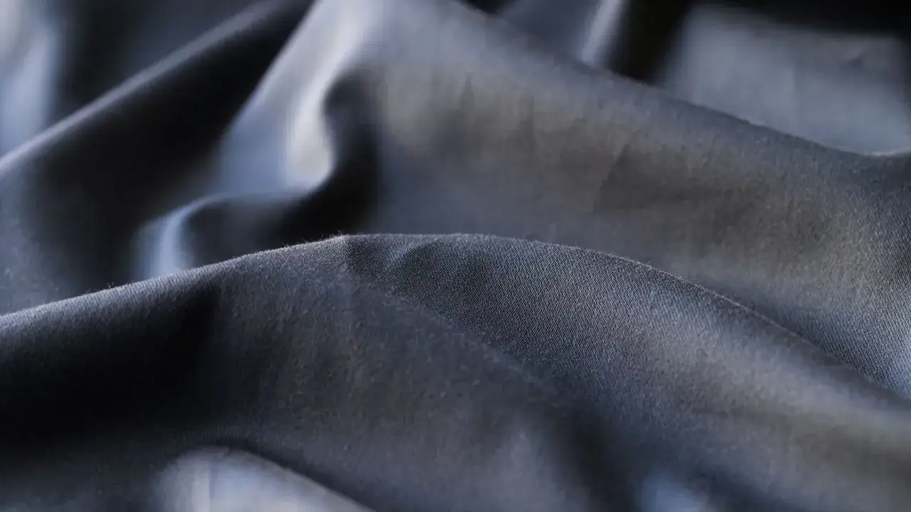 Dunkelgrauer, glatter Stoff mit Falten. Ist Polyester gut? Ja, f&uuml;r seine Strapazierf&auml;higkeit und Pflegeleichtigkeit.
