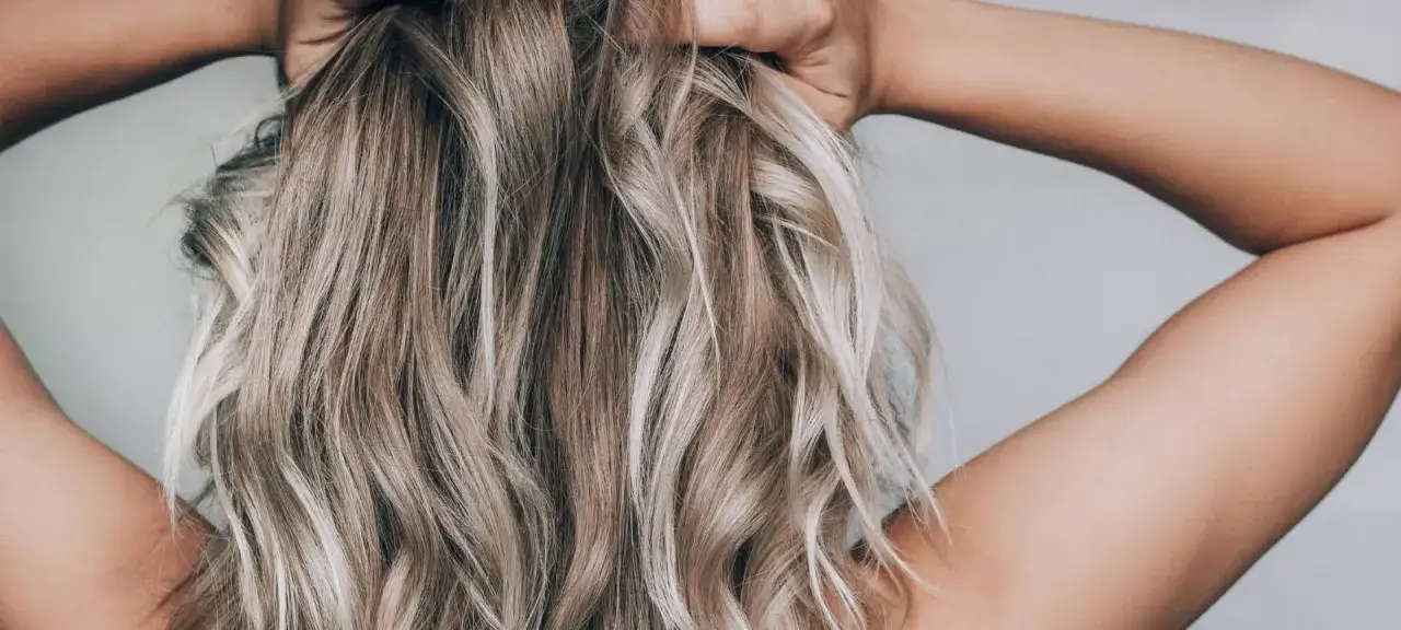 Frau pflegt gef&auml;rbtes Haar mit Shampoo und Conditioner