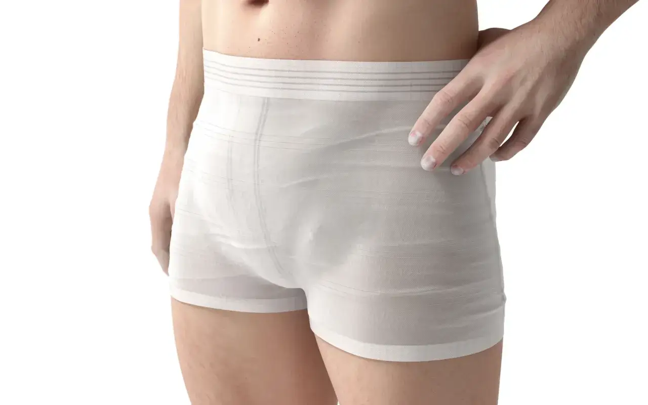 Un homme porte un slip ou boxer blanc, avec une main pos&eacute;e sur la hanche.