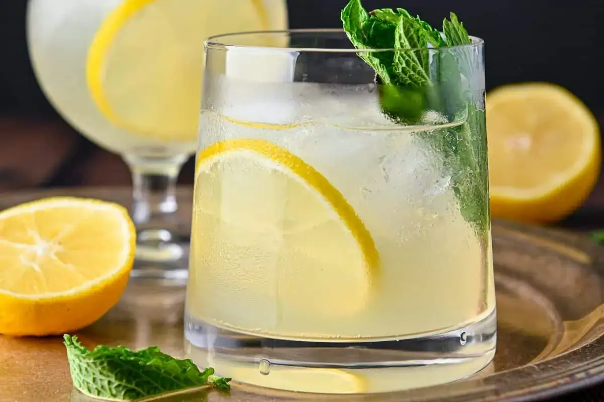 Erfrischender Limoncello Spritz mit Zitrone und Minze, serviert auf einem Silbertablett.