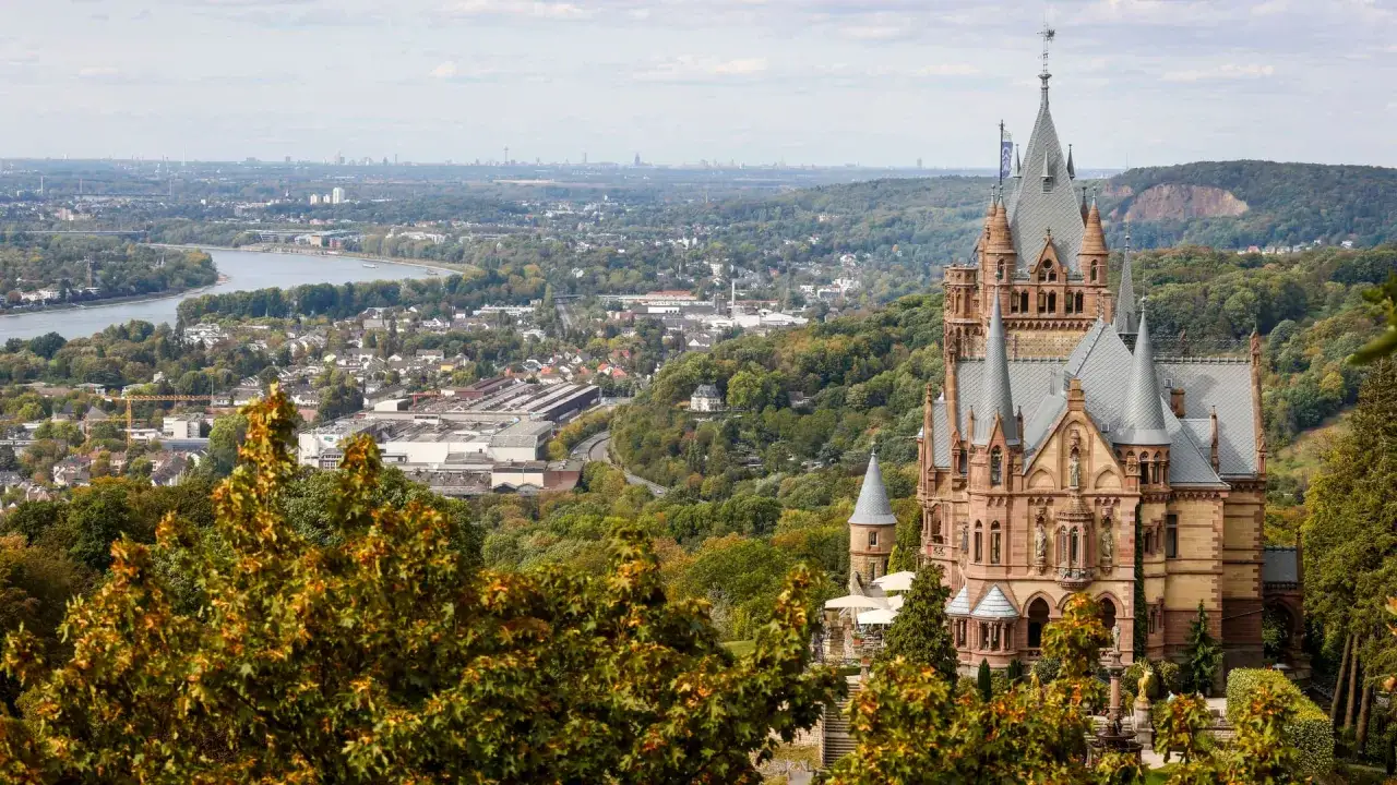 M&auml;rchenhafte Burg Drachenfels thront &uuml;ber dem Rheintal, umgeben von herbstlichem Gr&uuml;n.