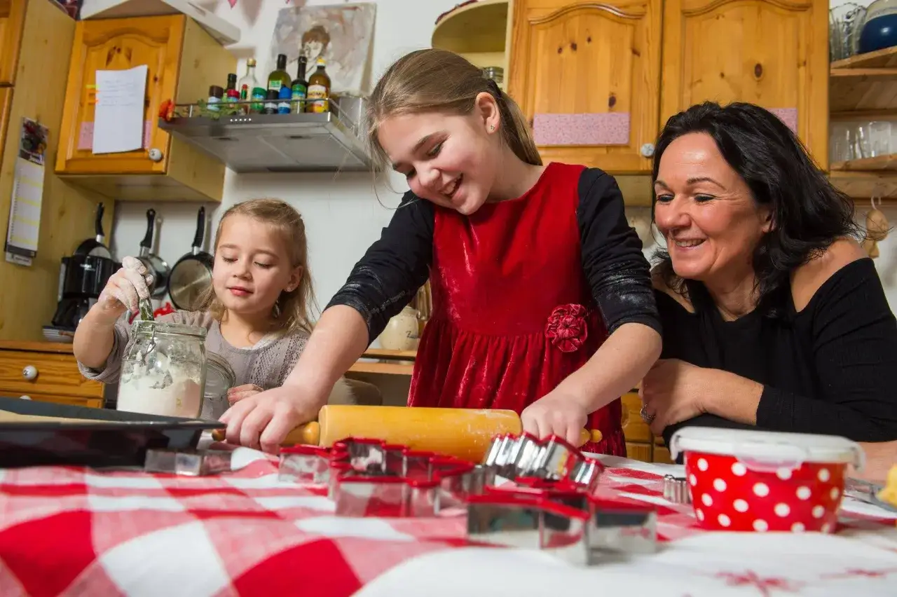 Familie backt Pl&auml;tzchen. Kinder helfen mit Mehl und Teig. Viel Spa&szlig; beim Backen mit Kindern!