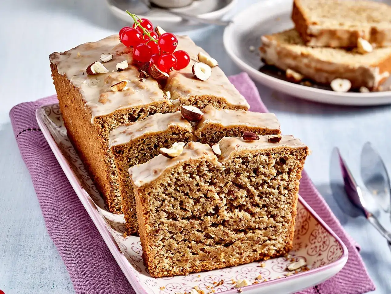Saftiger Kuchen ohne Mehl, verziert mit Zuckerguss, Nüssen und roten Johannisbeeren.