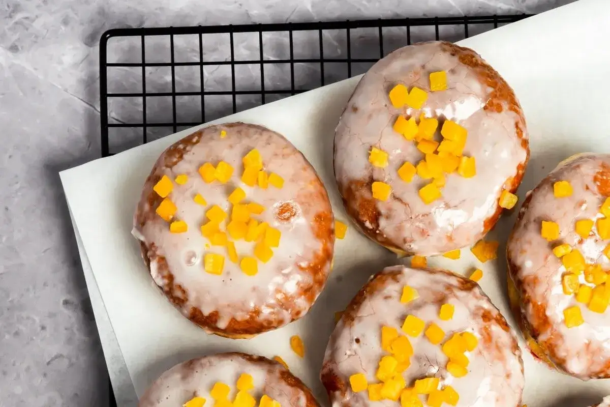Pączki z piekarnika, oblane lukrem i posypane kandyzowaną sk&oacute;rką pomarańczową, kuszą swoim wyglądem.
