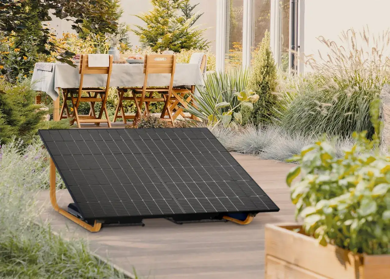 Un panneau solaire au sol, prêt à capter le soleil dans un jardin aménagé avec une table dressée pour un repas en plein air.