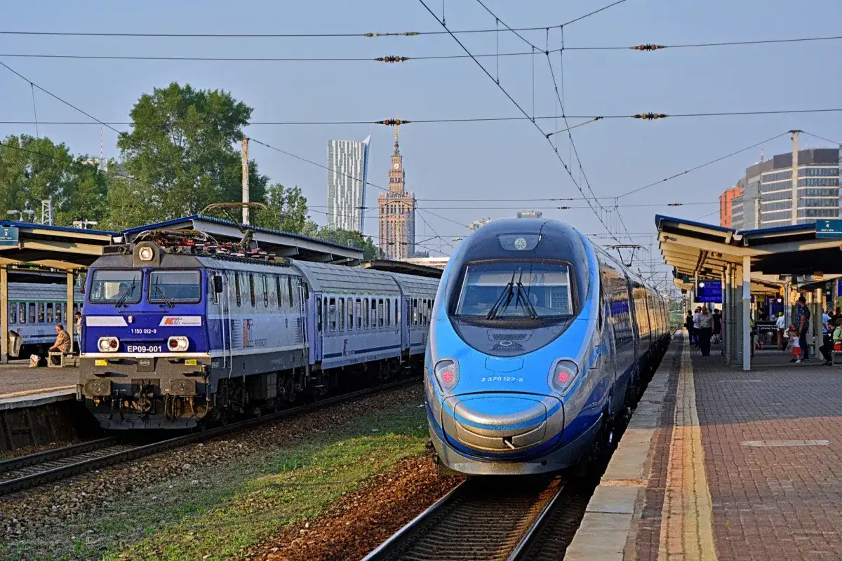 Dwa pociągi na stacji, jeden niebieski Pendolino, drugi niebiesko-szary. W tle wieżowce. Idealne, by sprawdzić, jak dojechać do Berlina.