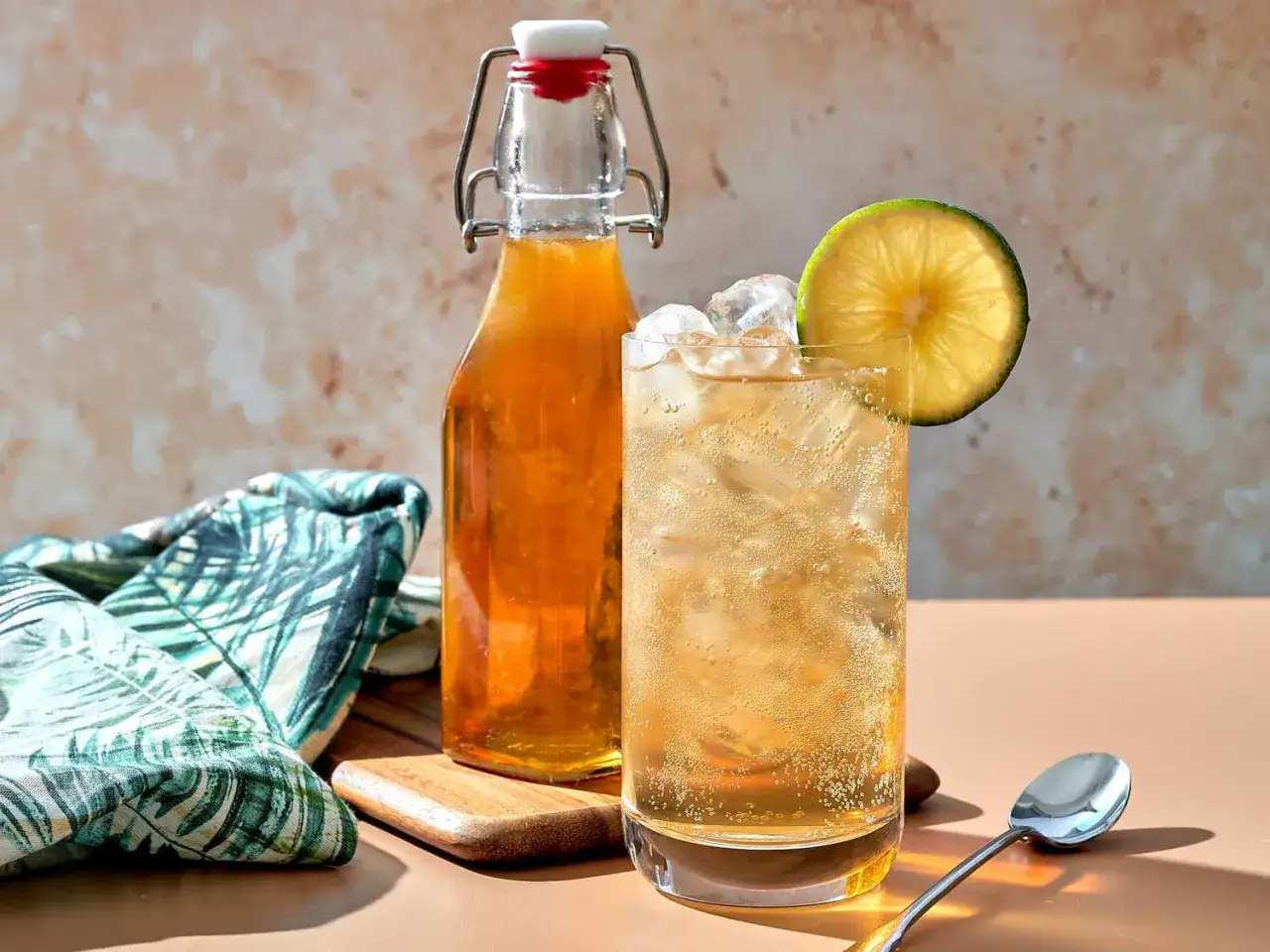 Erfrischendes Getränk mit Eis und Limettenscheibe, daneben eine Flasche. So schmeckt Tonic Water: prickelnd und leicht herb.