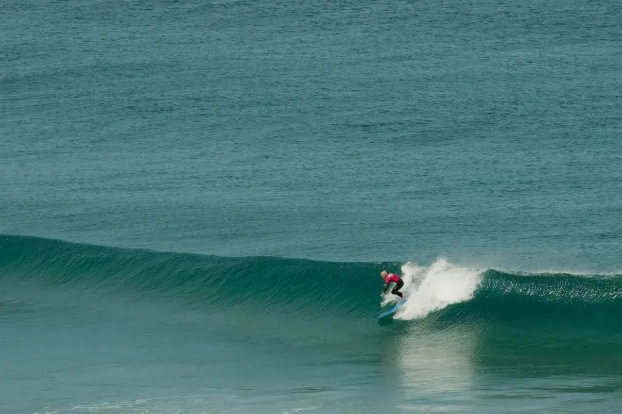 Surferin reitet eine Welle vor der Küste von Fuerteventura. Das costa calma surfen ist hier ein Erlebnis.