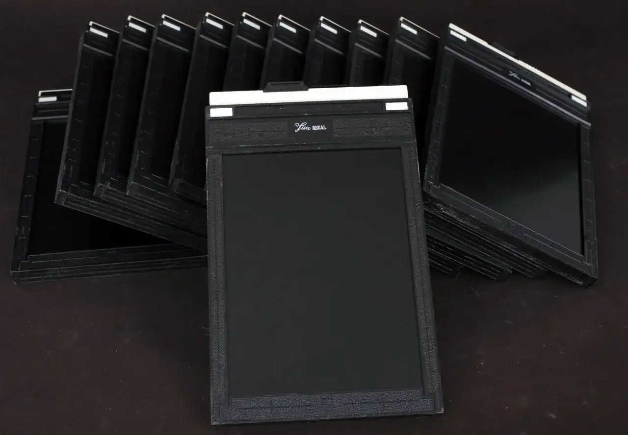 A stack of vintage 4x5 film holders, ready for a photographer's next masterpiece.