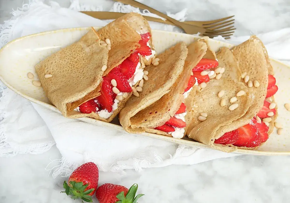 Deliciosos crepes con harina de almendras, rellenos de fresas frescas y queso crema, espolvoreados con pi&ntilde;ones.