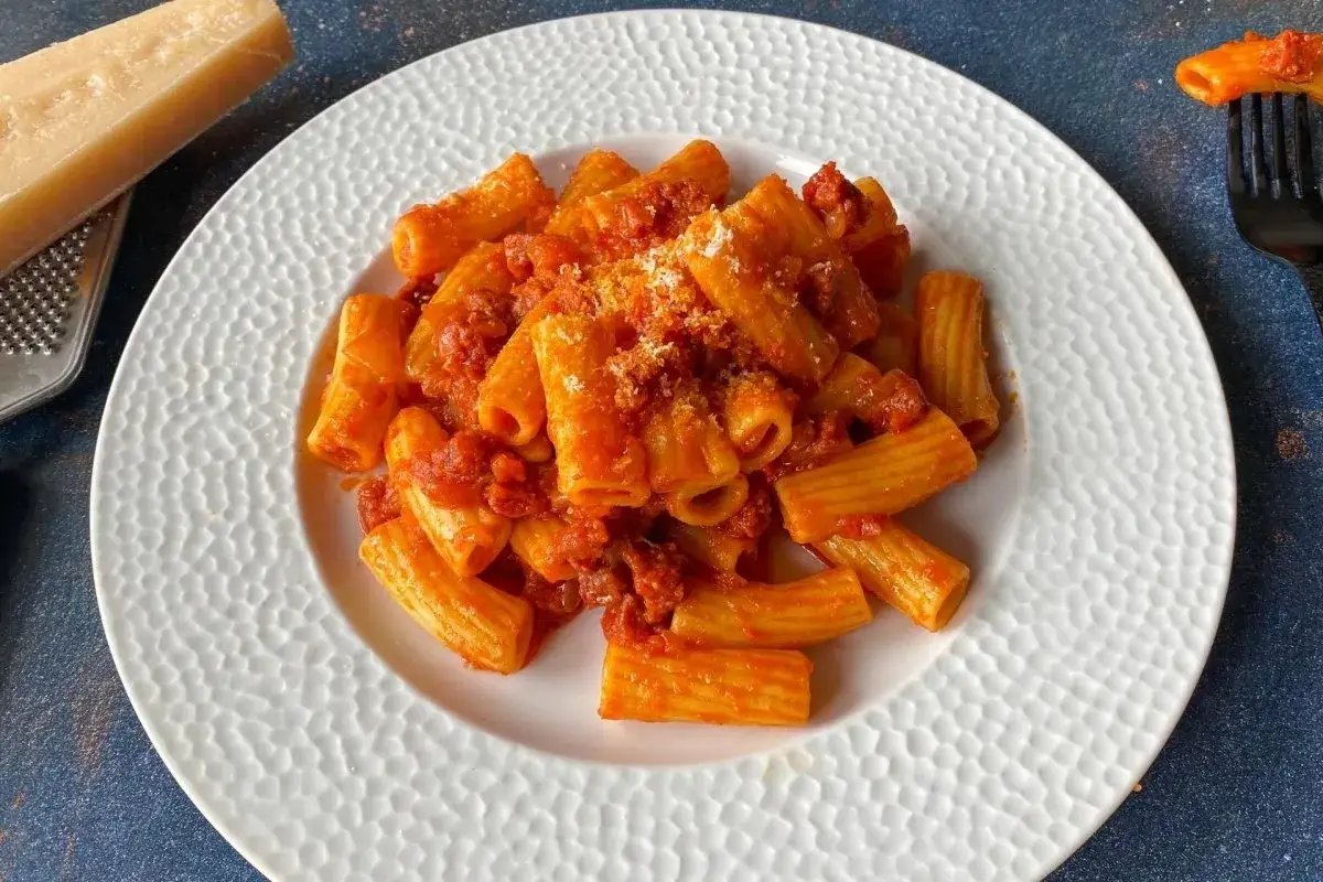 Un plato de rigatoni con una rica salsa de tomate y chorizo, espolvoreado con queso rallado.