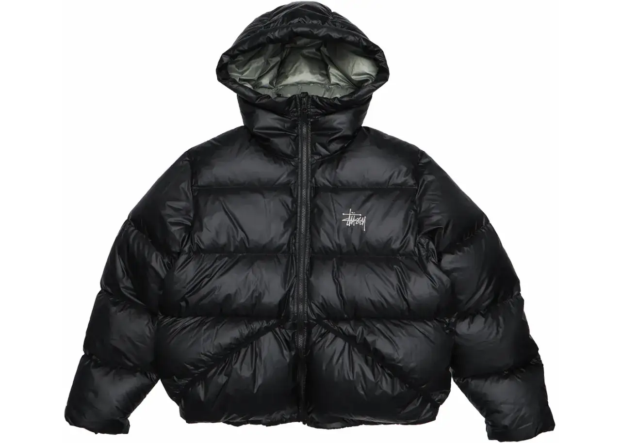 Piumino nero Stussy con cappuccio, logo bianco sul petto. Perfetto per affrontare il freddo con stile.