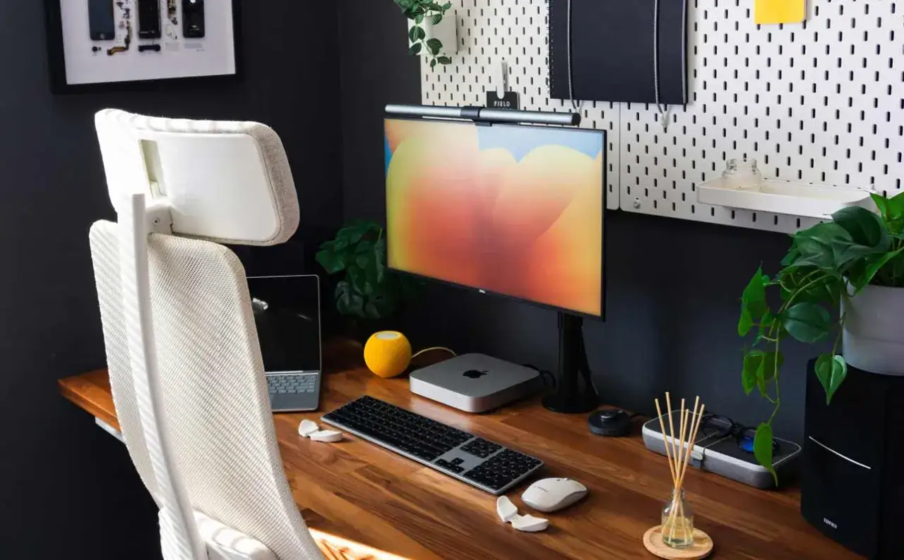 Ergonomiczne stanowisko do pracy zdalnej, zgodne z kodeksem pracy. Monitor, klawiatura, myszka, laptop i wygodne krzesło tworzą idealne miejsce do efektywnej pracy.