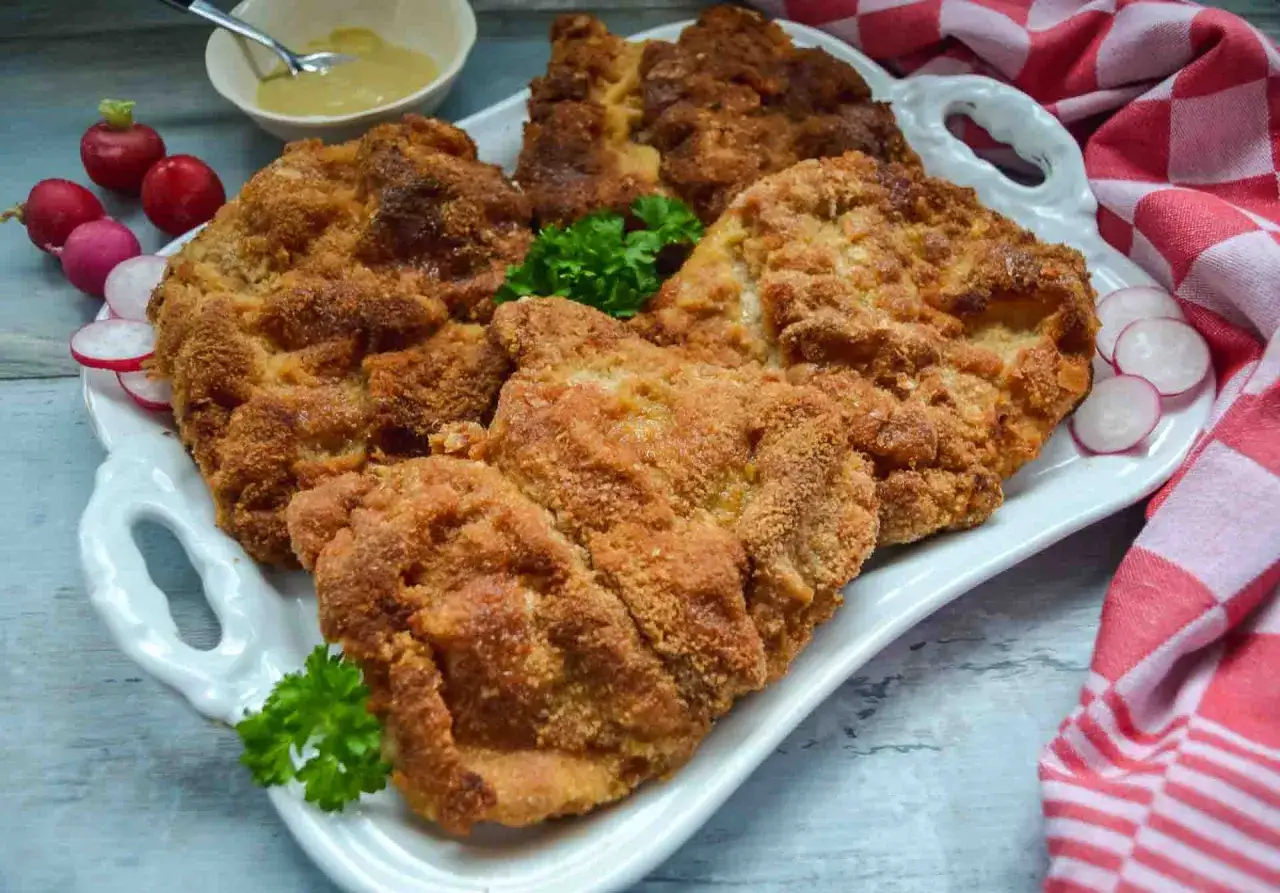 Goldbraun paniertes Schnitzel, perfekt zum **Schnitzel panieren**. Dazu Radieschen, Petersilie und Senf.