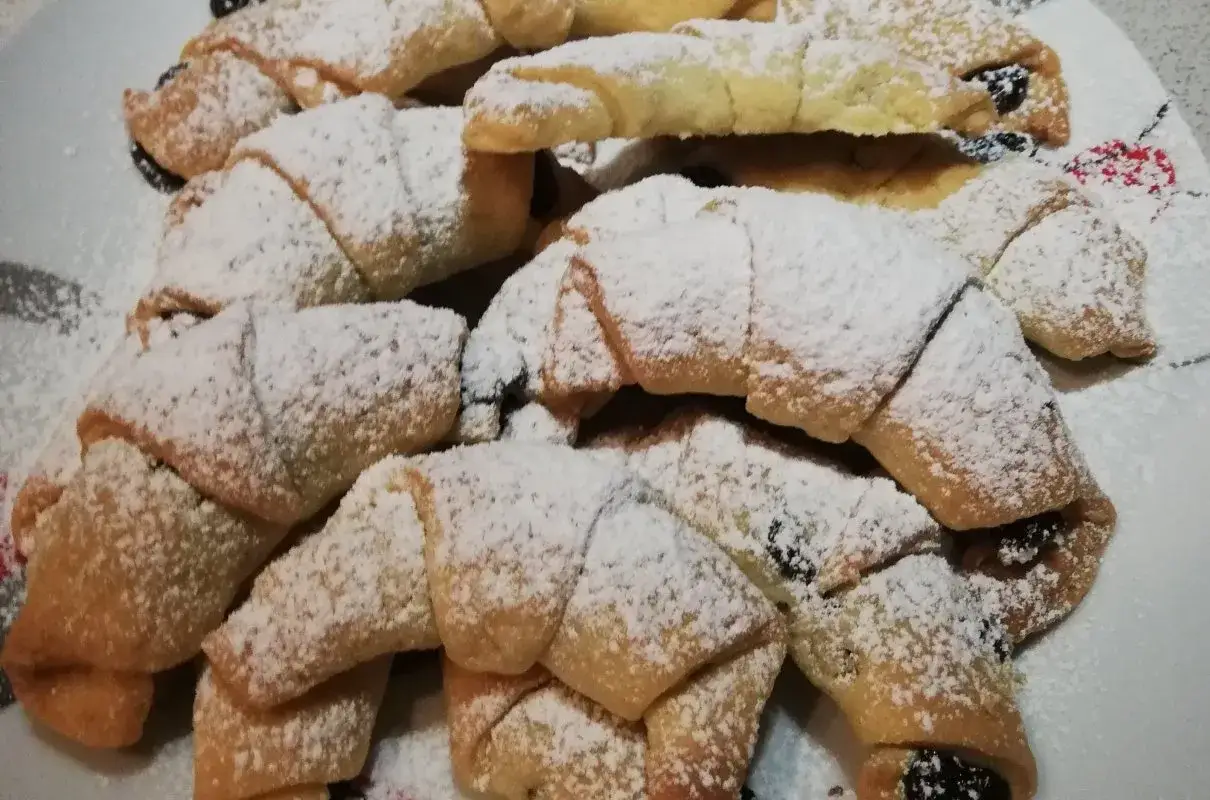 Stos puszystych, szybkich rogalików kruchych, posypanych cukrem pudrem. Idealne na szybką przekąskę.