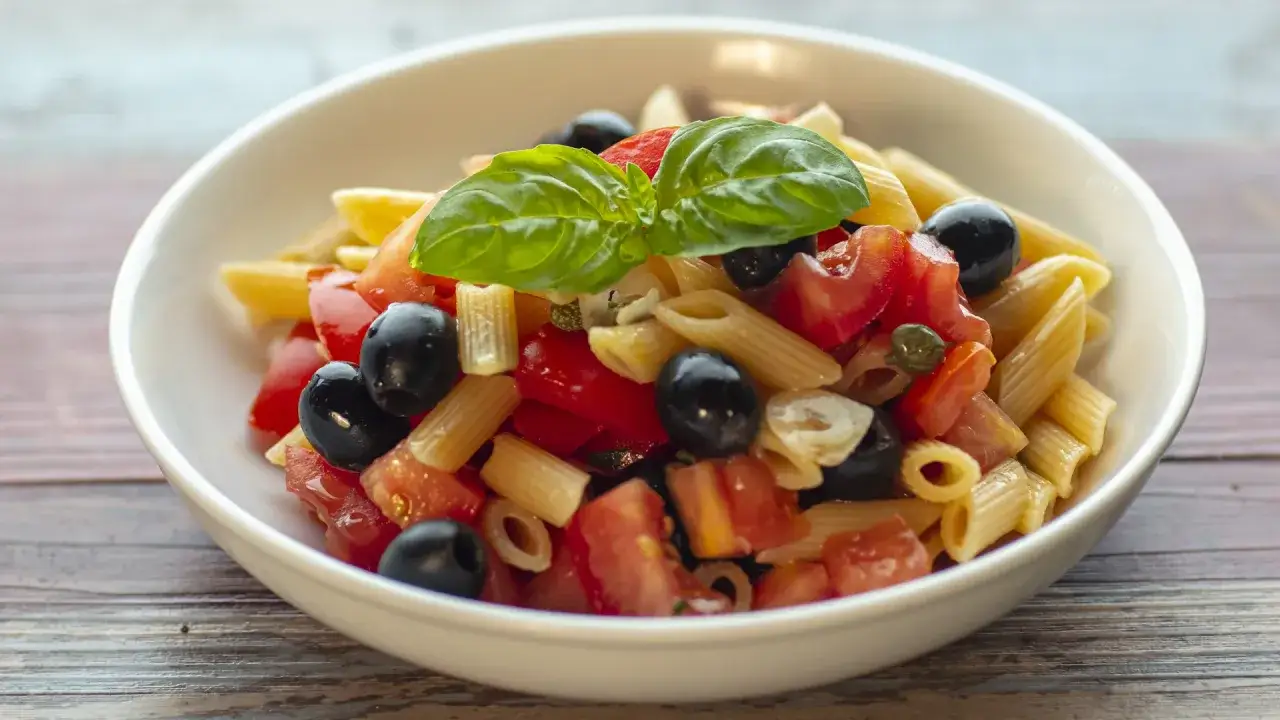 Penne con pomodoro fresco, olive nere, capperi e basilico, un delizioso sugo alle olive.