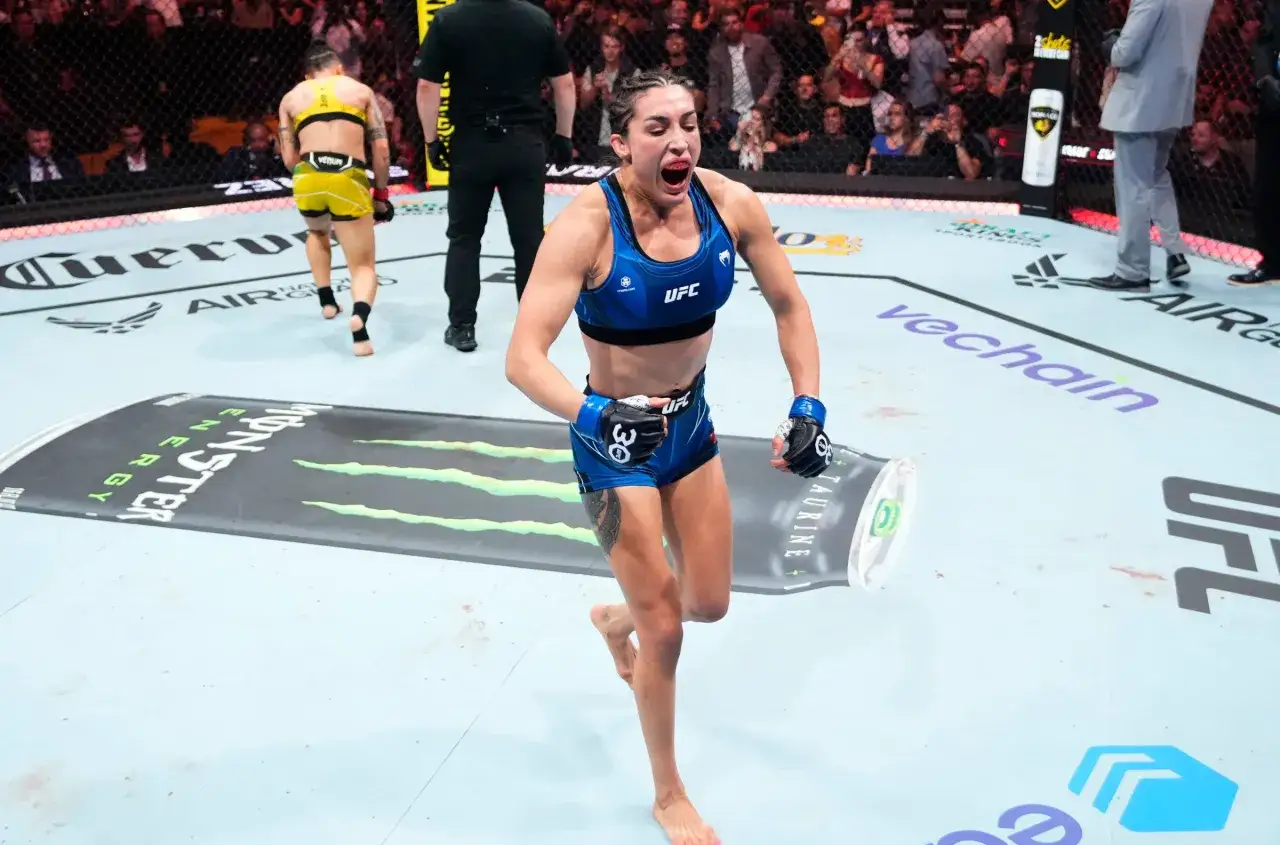 Tatiana Suarez firar en seger i oktagonen, med publiken i bakgrunden.
