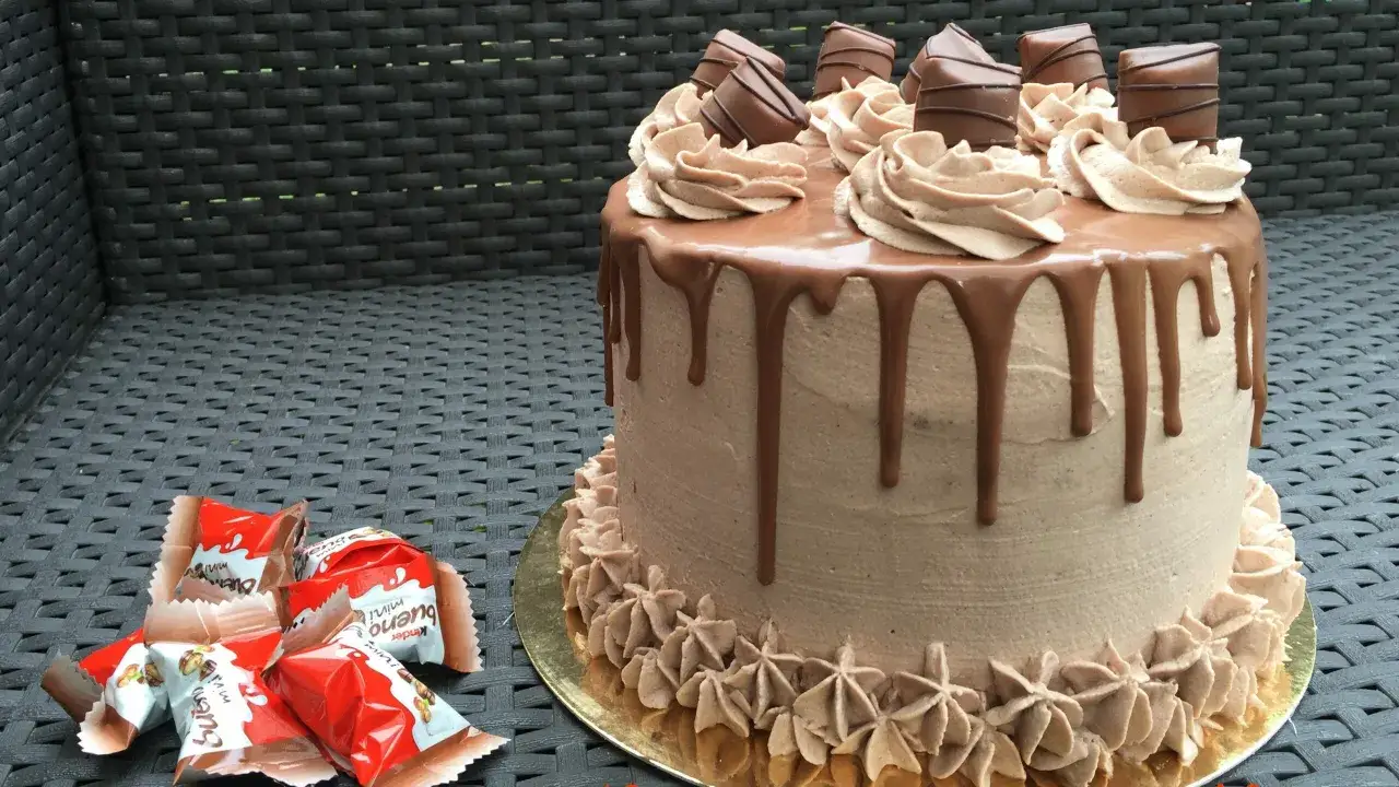 G&acirc;teau au chocolat avec ganache et morceaux de Kinder Bueno, d&eacute;cor&eacute; de cr&egrave;me au beurre et de gouttes de chocolat.