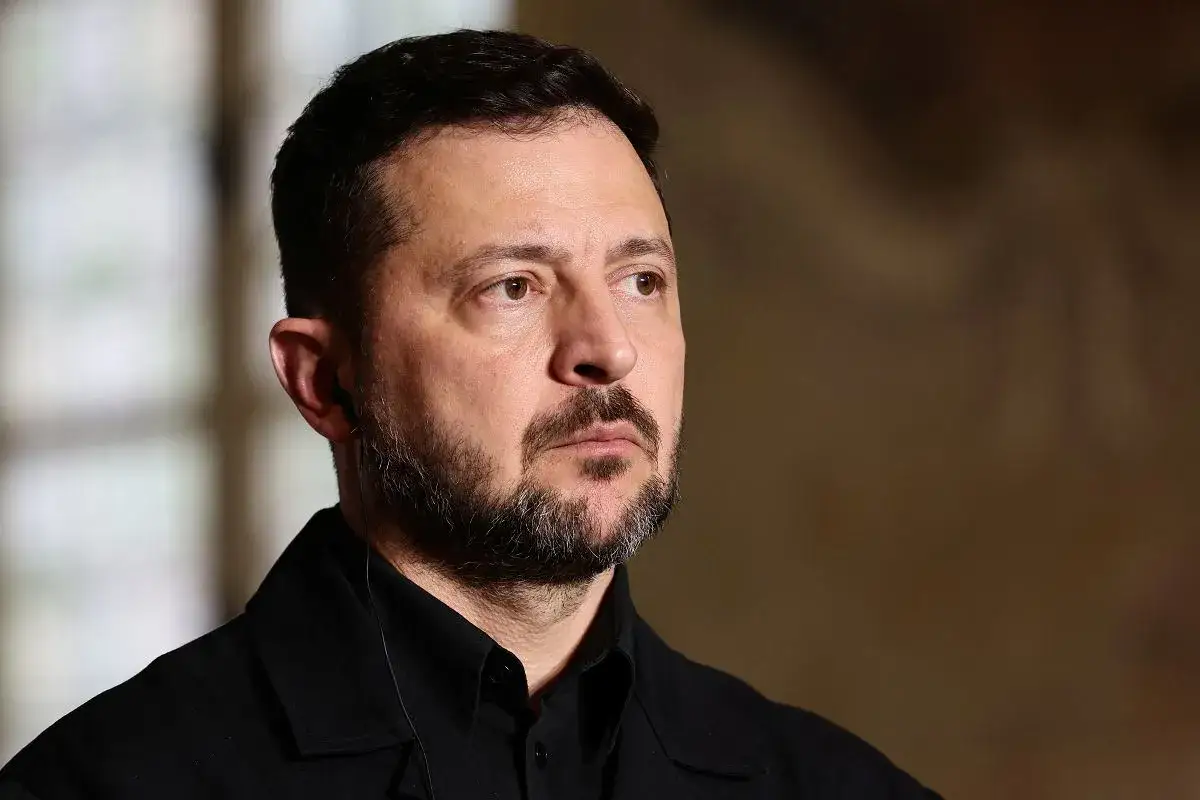 Prezydent Ukrainy Wołodymyr Zełenski w czarnym ubraniu, z zarostem i słuchawką w uchu.