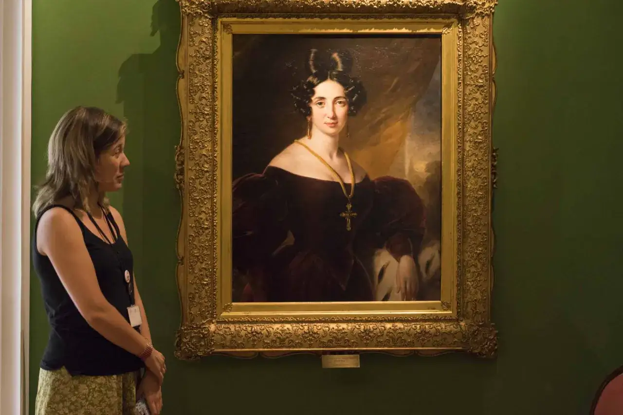 Una mujer observa un retrato de dama, un ejemplo de cuadros del romanticismo.