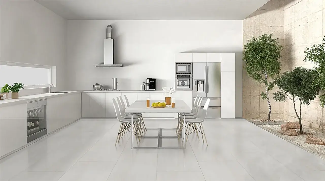 Cocina moderna y luminosa con encimeras blancas, electrodom&eacute;sticos integrados y una mesa de comedor. Los suelos para cocinas blancas reflejan la luz, creando un ambiente espacioso y limpio.