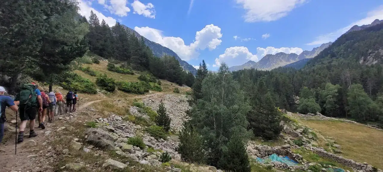 Senderismo por el **valle de Madriu-Perafita-Claror**, un paisaje monta&ntilde;oso con bosques, rocas y un cielo azul con nubes.