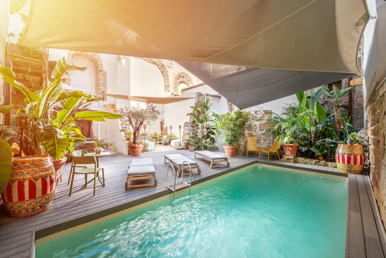 Cortile con piscina e lettini, ideale per scoprire dove alloggiare a Palermo e godersi il relax.