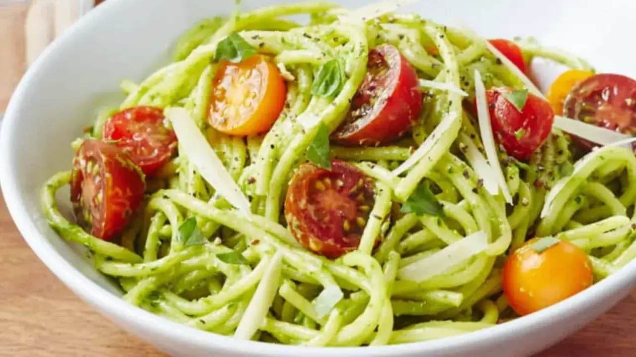 Eine Schüssel cremiger Avocado Pasta mit Kirschtomaten und Parmesan.