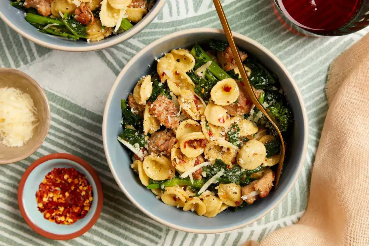 Orecchiettepasta med korv och gröna bladgrönsaker, toppad med parmesan. Ett perfekt middagstips för en snabb och smakrik måltid.