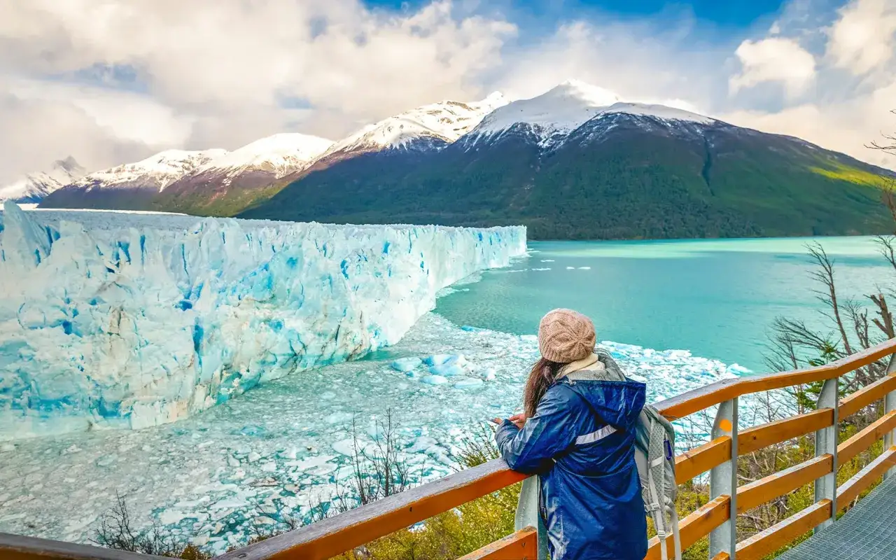 Una persona admira la majestuosidad del glaciar Perito Moreno, con sus imponentes paredes de hielo azul y monta&ntilde;as nevadas al fondo.