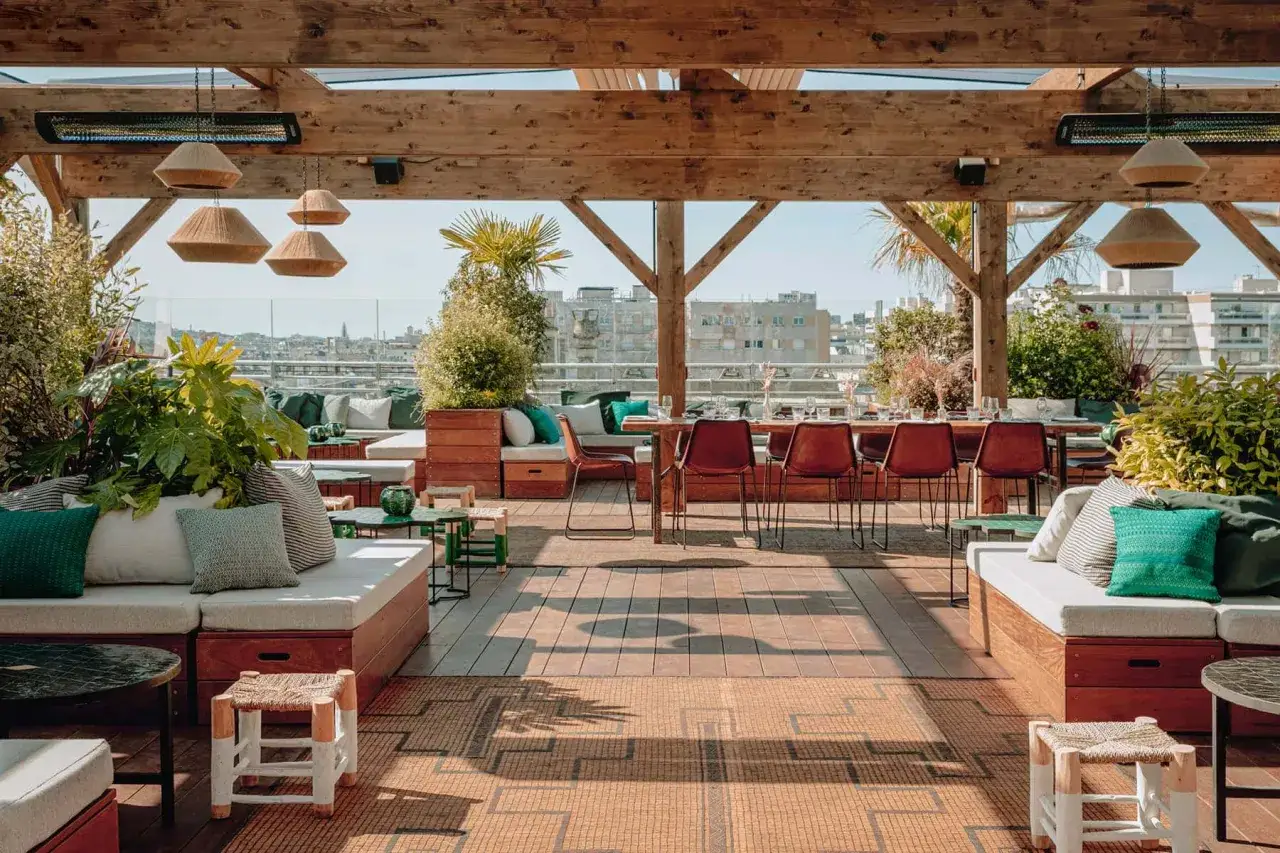 Le perchoir Ménilmontant : un rooftop chic avec vue sur Paris, mobilier confortable, verdure luxuriante et tables dressées pour un moment suspendu.