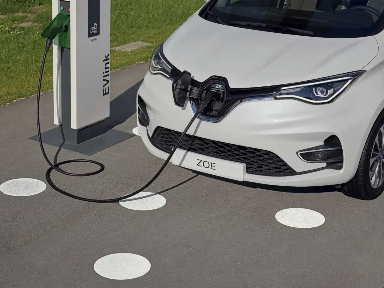 Białe Renault Zoe ładuje się przy stacji EVlink.