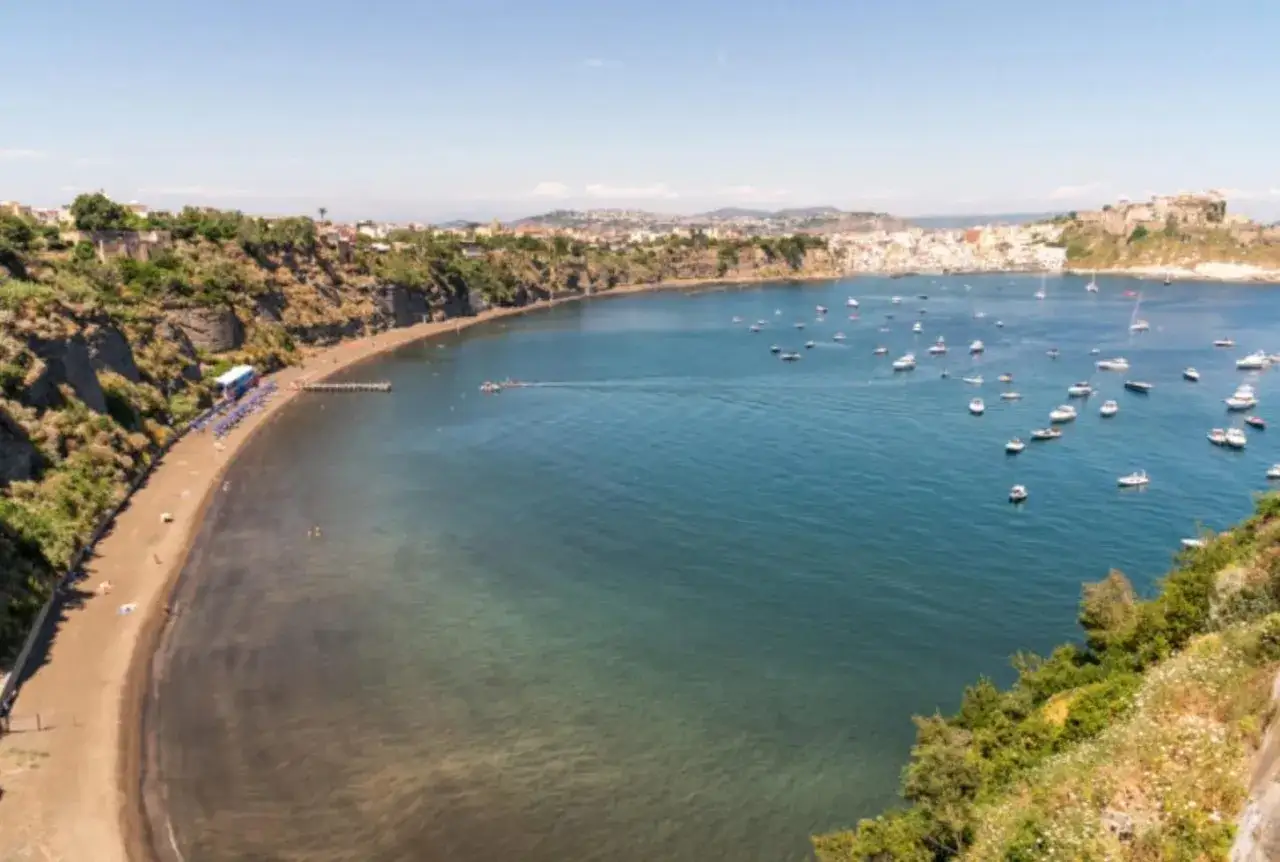 Vue d'une baie pittoresque avec une plage de sable noir, des falaises verdoyantes et une multitude de bateaux ancr&eacute;s, une charmante voisine de Capri.
