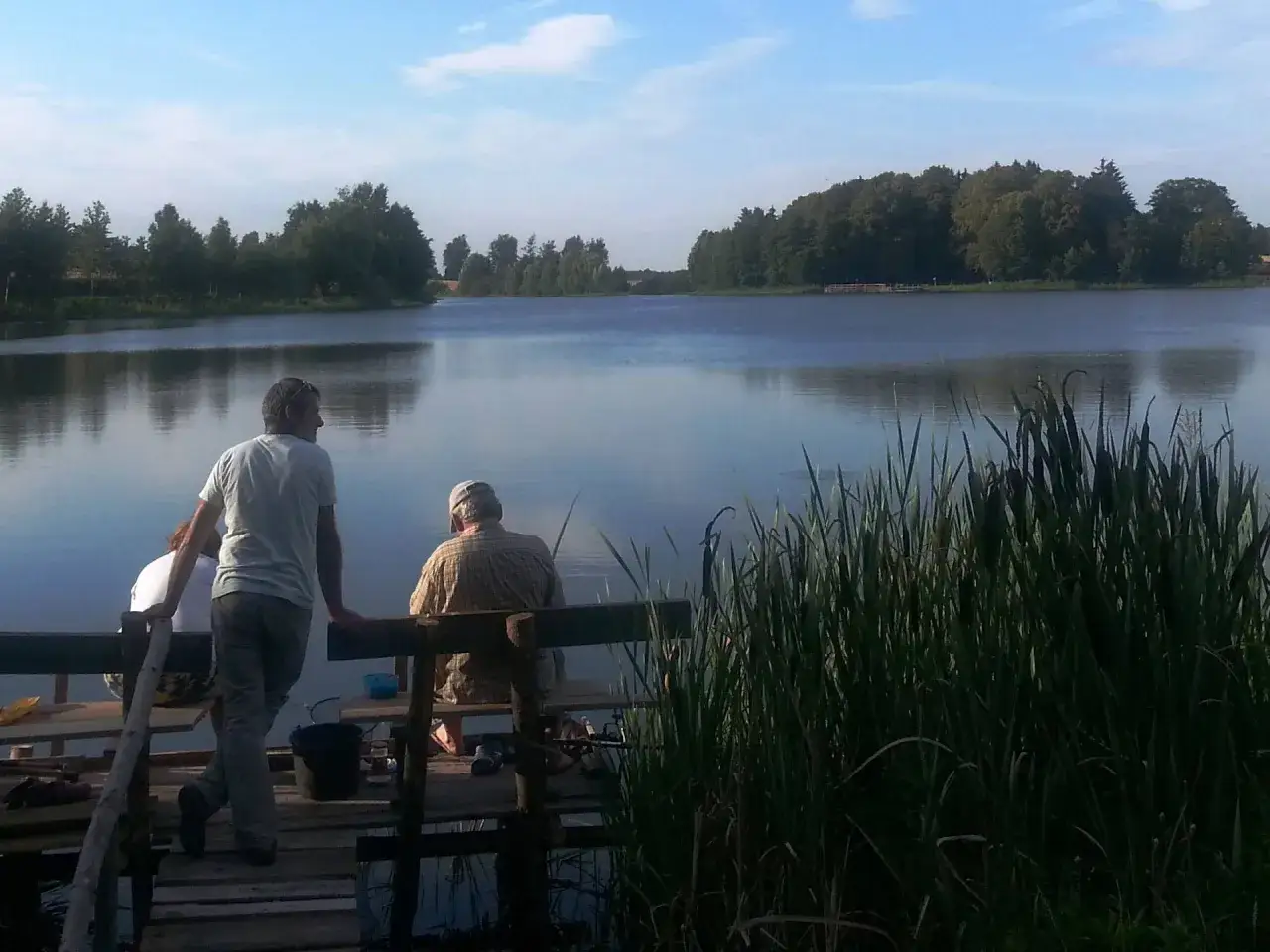 Spokojny poranek nad jeziorem Przechlewskim. Dwóch wędkarzy czeka na branie, otoczeni zielenią i spokojną taflą wody.