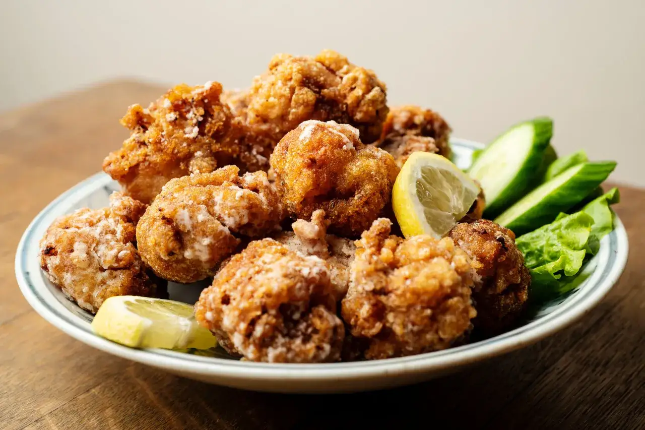 A plate of crispy nanban food, featuring golden-brown fried chicken pieces, garnished with lemon wedges and fresh cucumber slices.