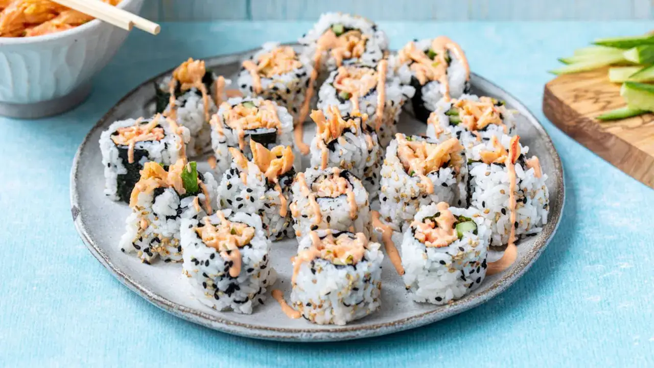 Talerz sushi z surimi, polany sosem. Czy surimi jest zdrowe? To zależy od składników.