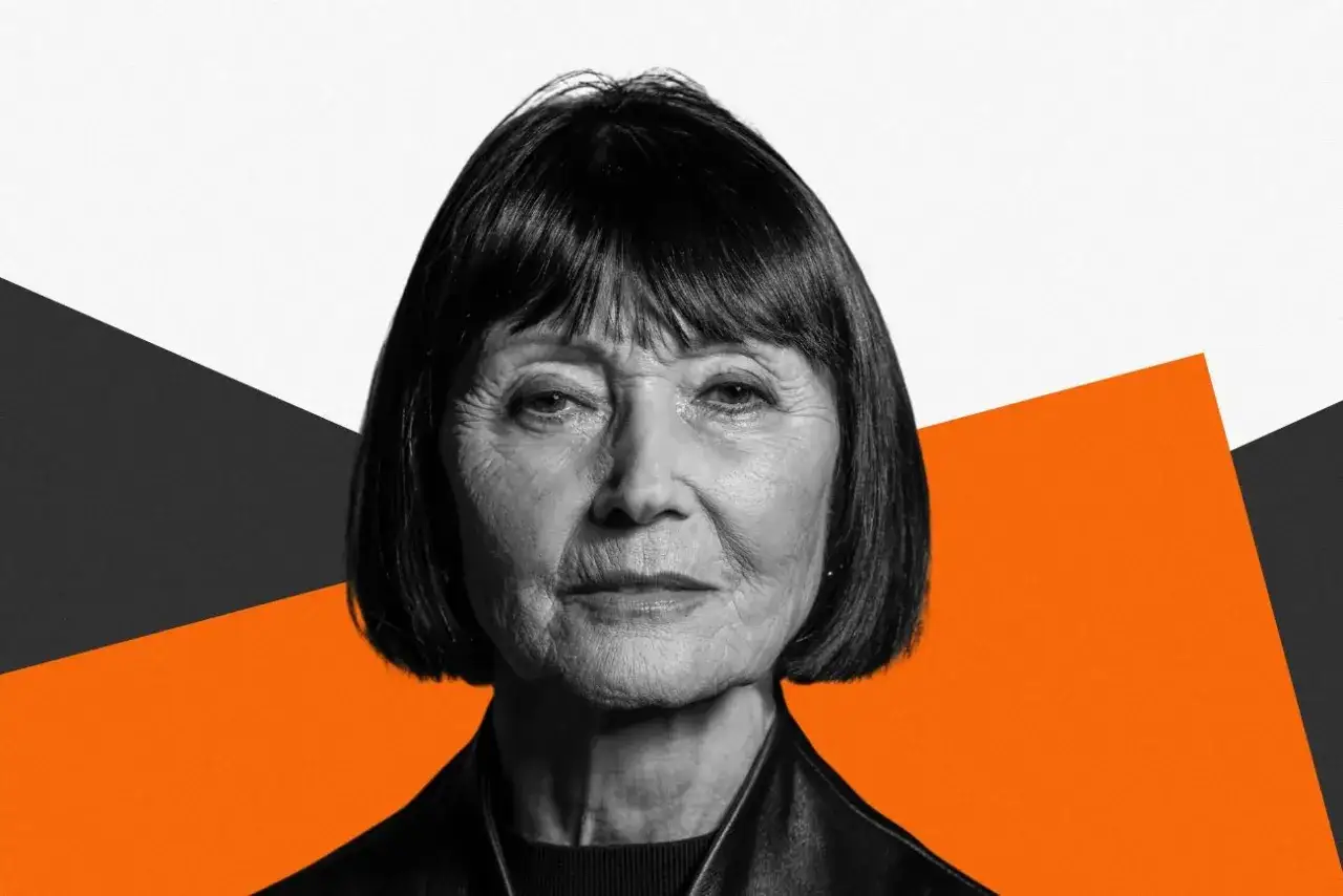 Portret Ewy Woydyłło, kobiety o wyrazistych rysach i krótkich włosach, na tle geometrycznych kształtów. Jej życie prywatne jest tematem, który intryguje.