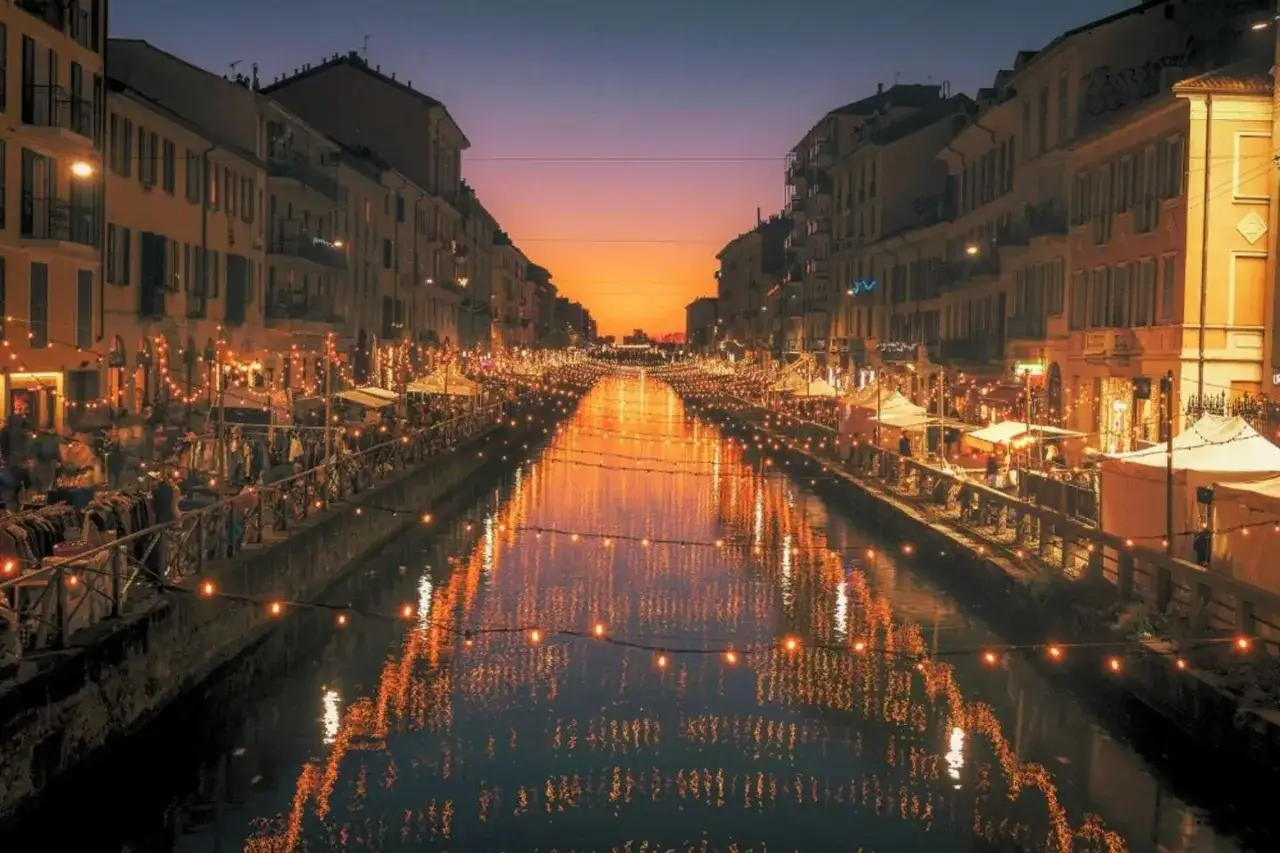 Marché nocturne animé le long des canaux de Milan, une idée de que faire a Milan. Lumières scintillantes sur l'eau au crépuscule.