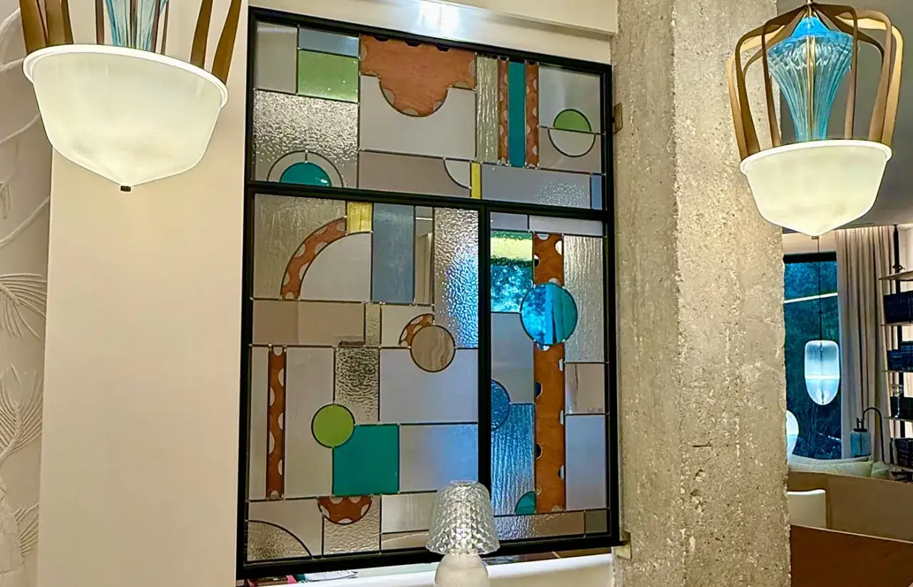 Vitrail moderne aux formes géométriques et couleurs vives, évoquant un atelier vitrail Paris.