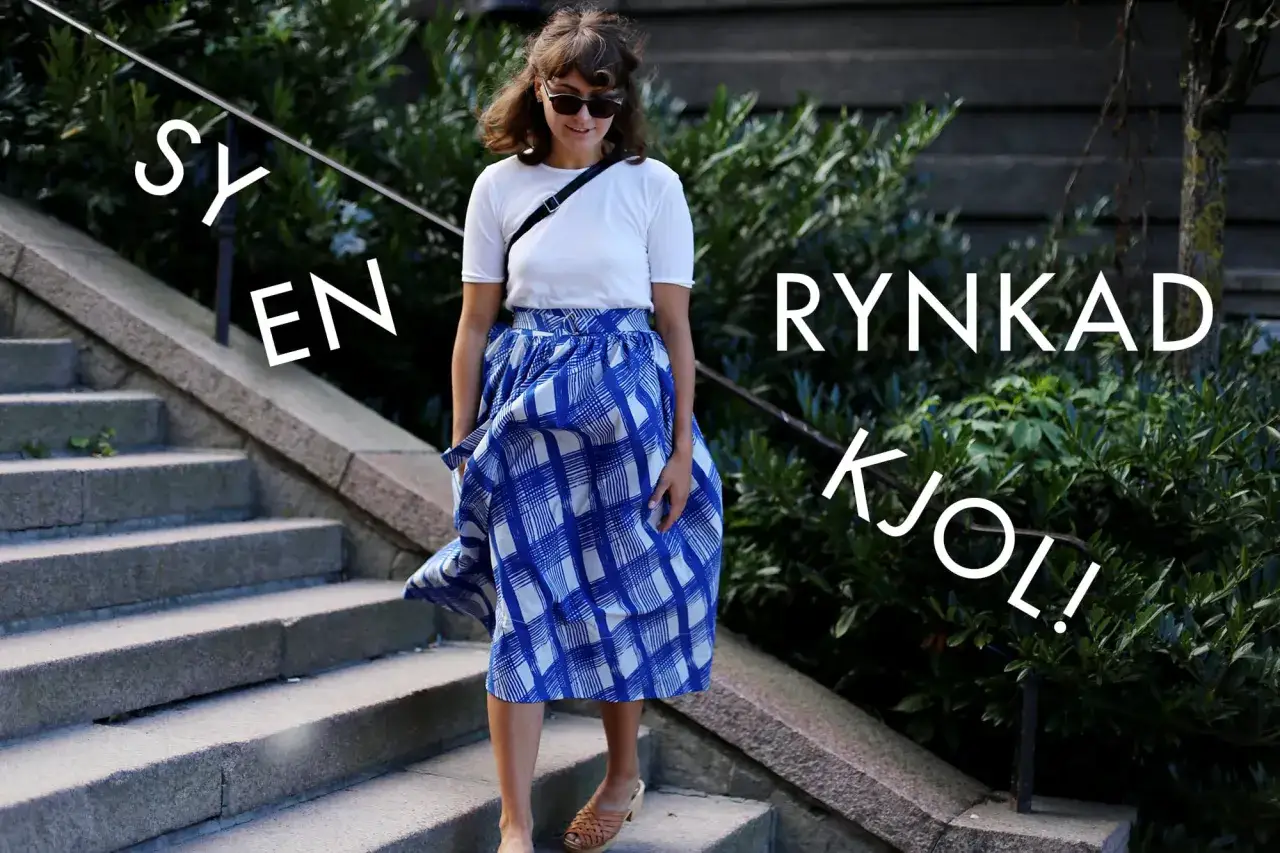 En kvinna går nerför en trappa i en rynkad kjol i trikå med blått rutmönster.