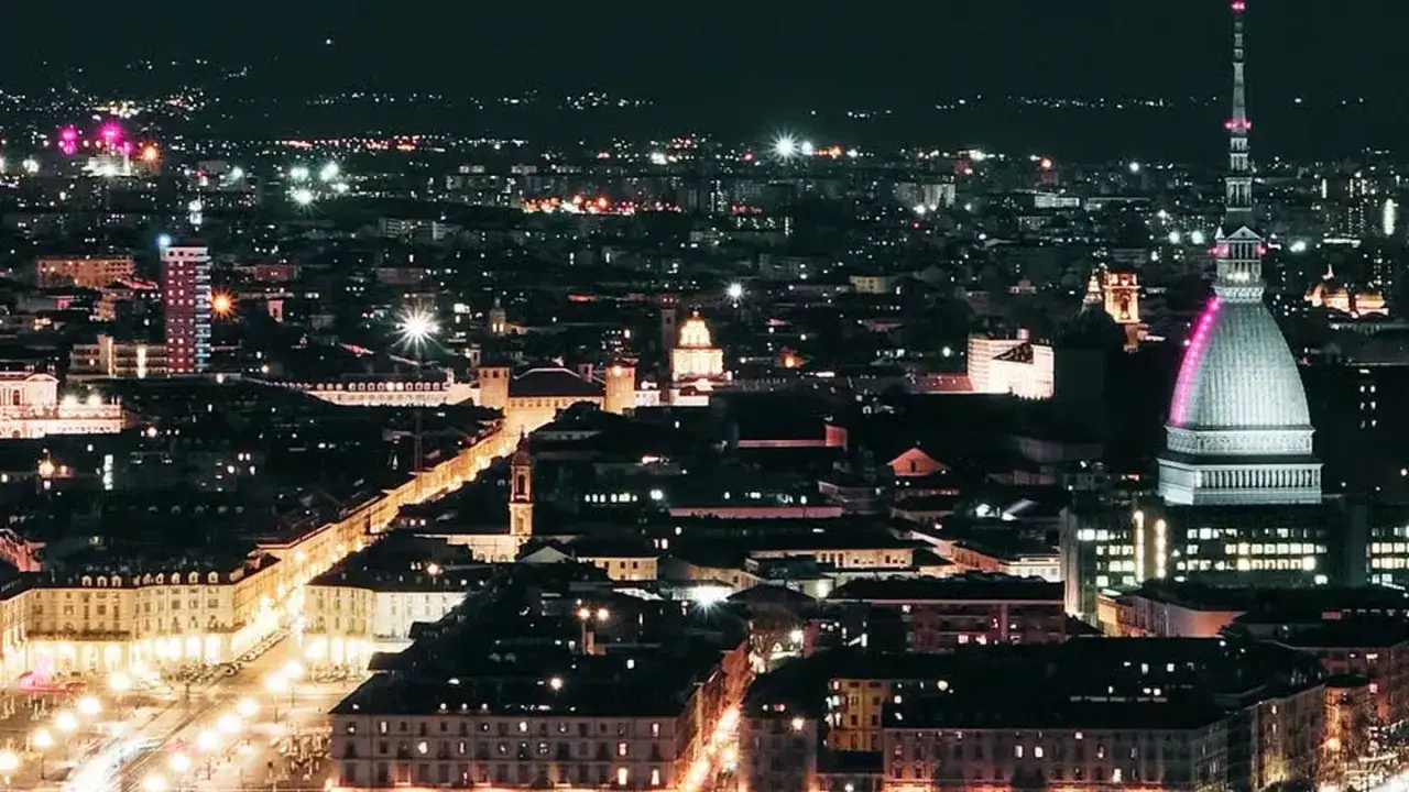 Torino illuminata di notte, con la Mole Antonelliana in primo piano. Un panorama suggestivo, perfetto per scoprire i migliori bar di Torino.