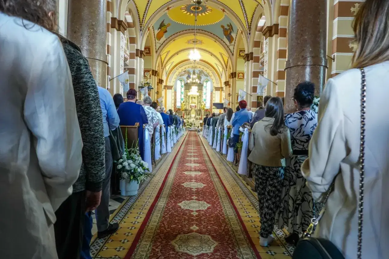 Ludzie w kościele, w białych szatach i eleganckich strojach, stoją w kolejce do ołtarza. To z pewnością ważne **święta nakazane**, które gromadzą wiernych.