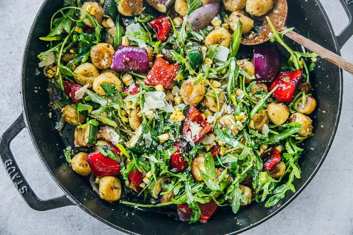 Herzhafter Gnocchi Salat mit ger&ouml;stetem Gem&uuml;se, Rucola und Parmesan in einer Pfanne.