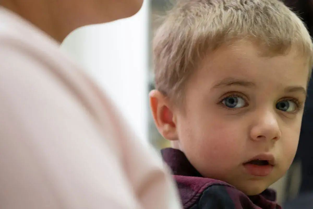 Bambino con occhi azzurri guarda con preoccupazione, un'immagine che evoca la necessità di sapere come difendere un figlio da un padre narcisista.